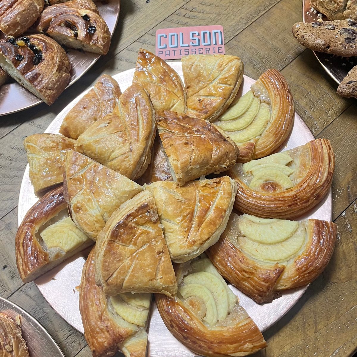 A copper platter of apple danishes and golden scored puff pastries, seen from above